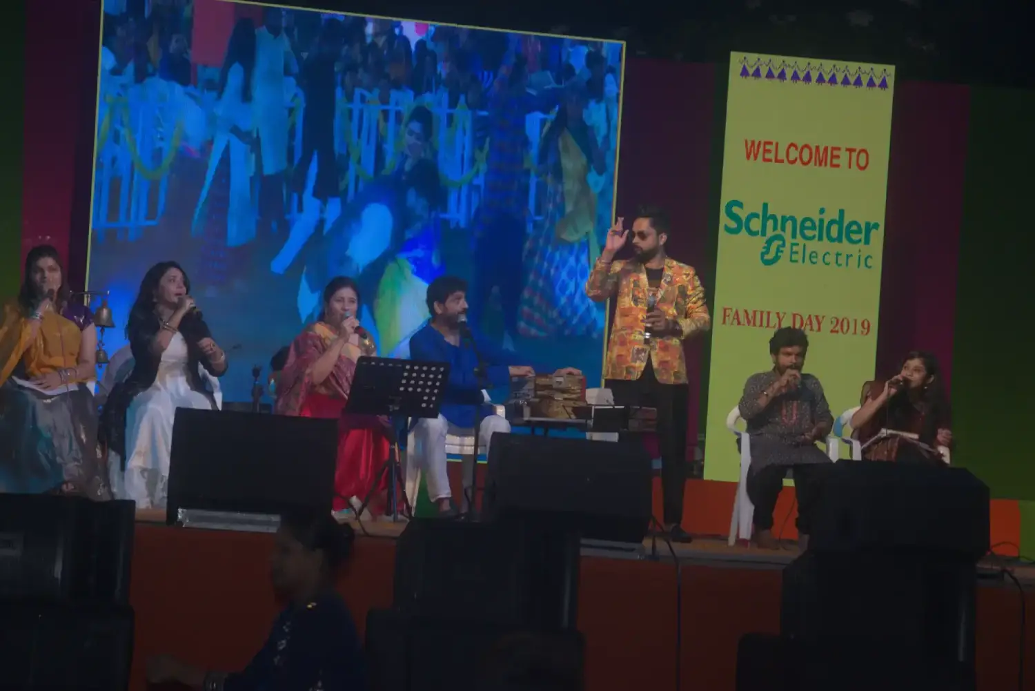 Man and woman speaking on stage at night with blue lighting